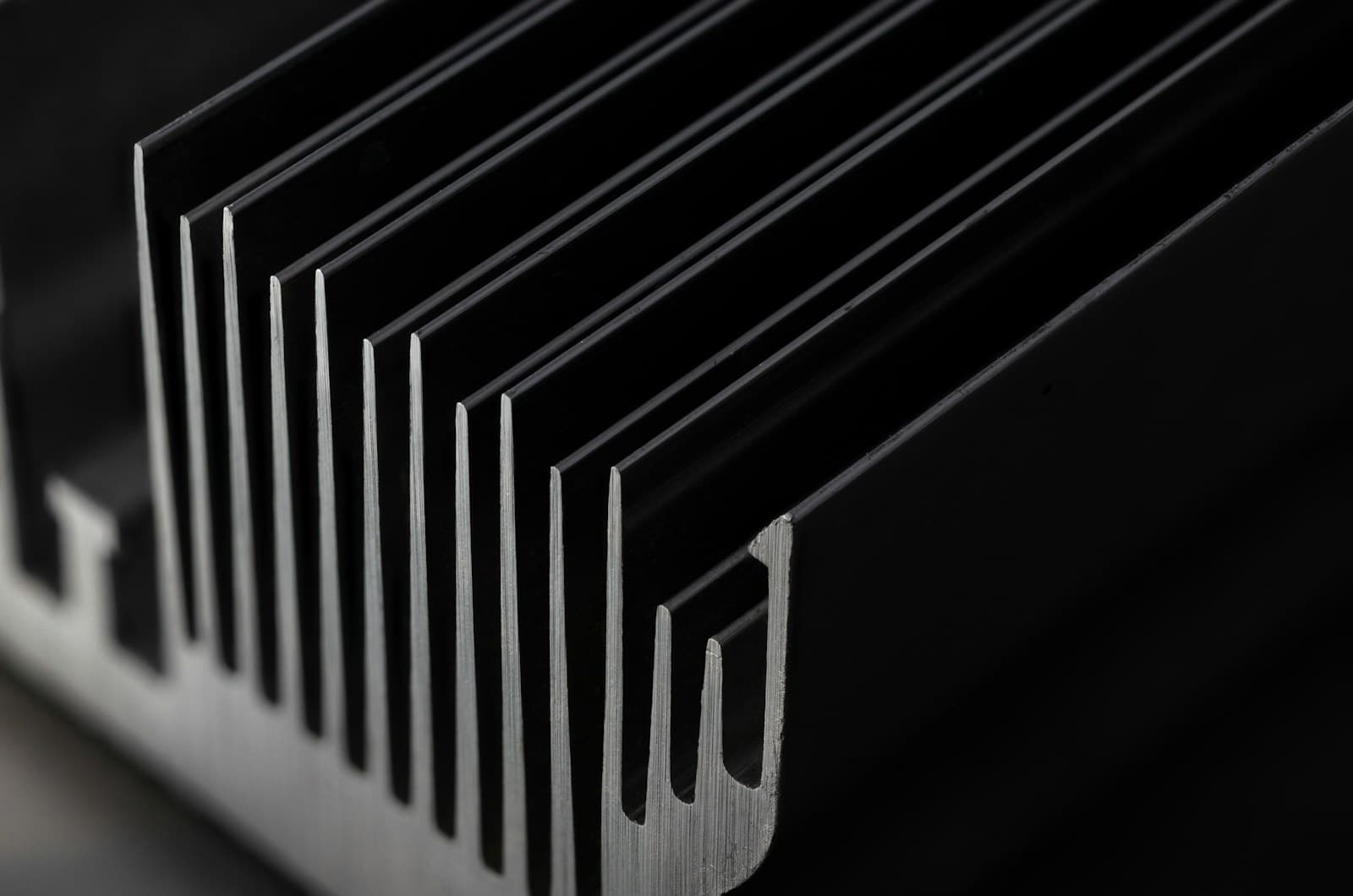 Close-up of aluminium heat sink fins standing in parallel against a dark ground.